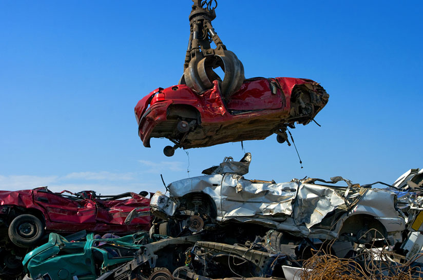 Kran hebt Auto auf Schrottplatz für thyssenkrupp und Novelis Recycling-Initiative.